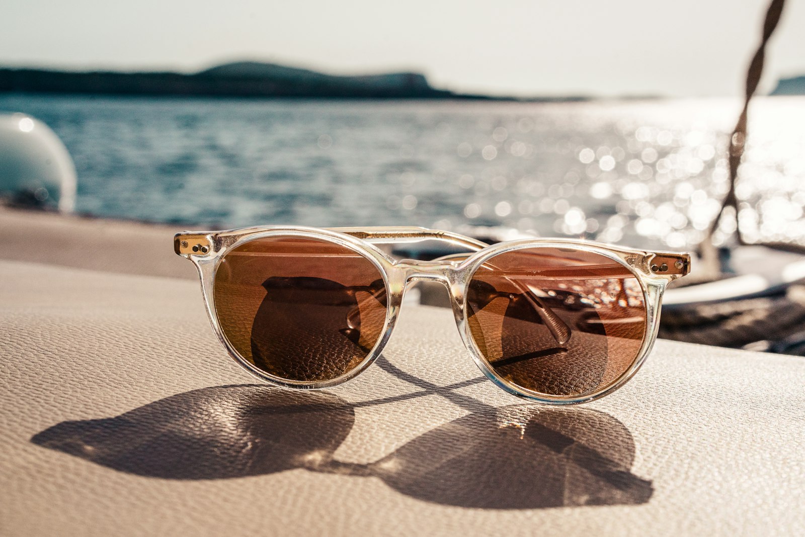 Clear-frame sunglasses resting by the water at golden hour
